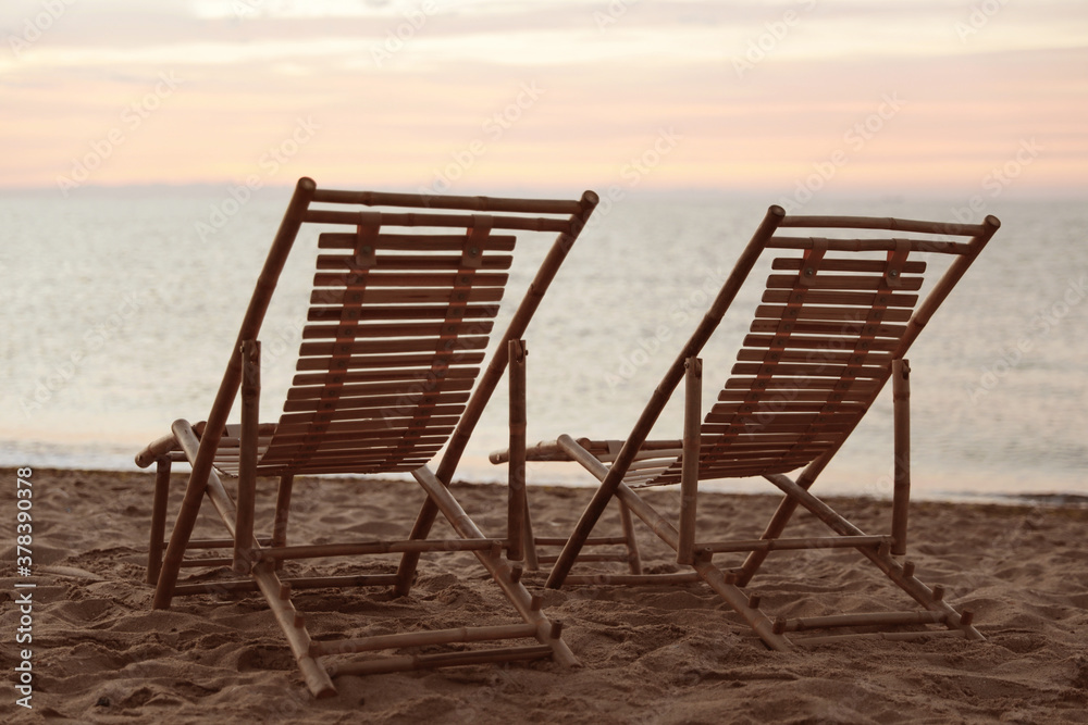 Wooden deck chairs on sandy beach at sunset. Summer vacation - obrazy, fototapety, plakaty 