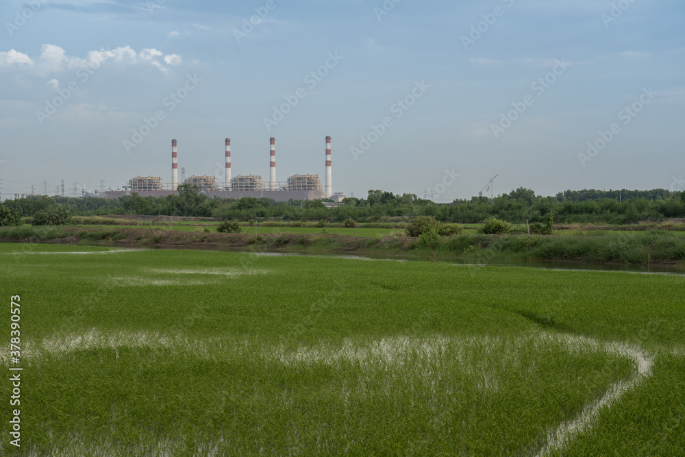 Power plant with green field againts sky