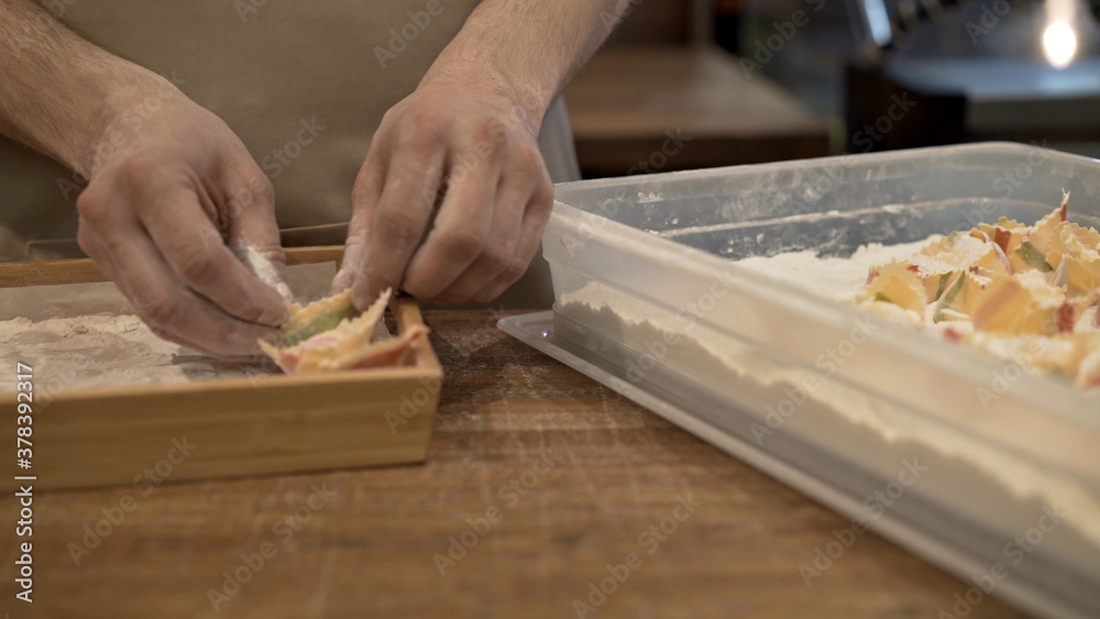 Male hands in flour on several tortellini in the tray with flour. Preparation of italian food at the restaurant kitchen, cooking italian ravioli