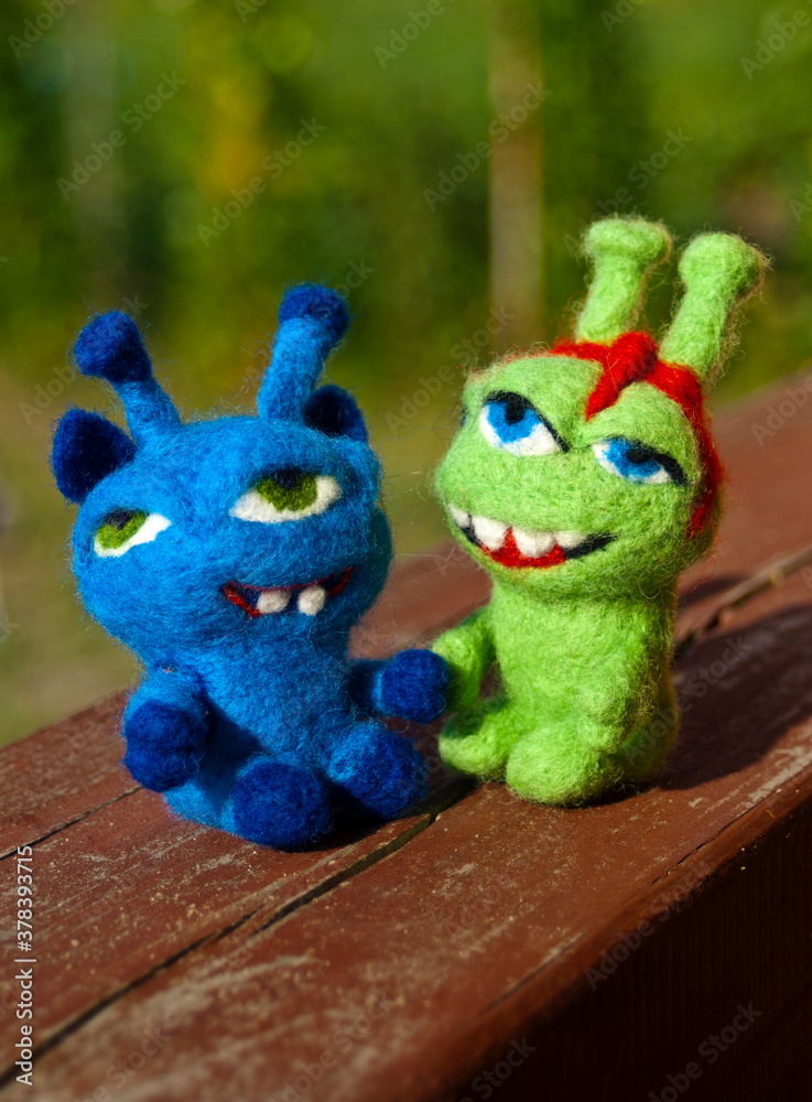 A couple of funny smiling handmade felted toy monsters