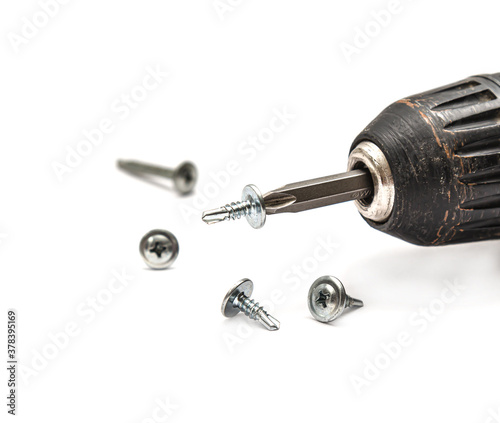 Screws for metal and electric hand screwdriver on a white background