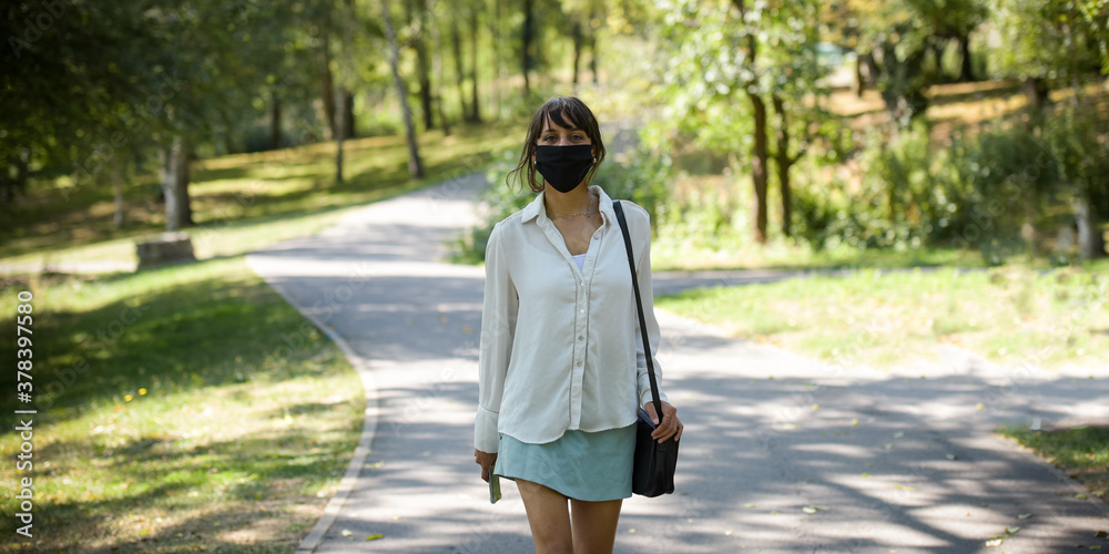 young woman protecting herself of covid with a mask in a park young woman protecting herself of covid with a mask in a park