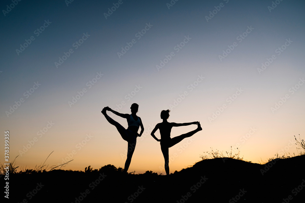 Silhouette women practicing hand to big toe pose against clear sky Silhouette women practicing hand to big toe pose against clear sky