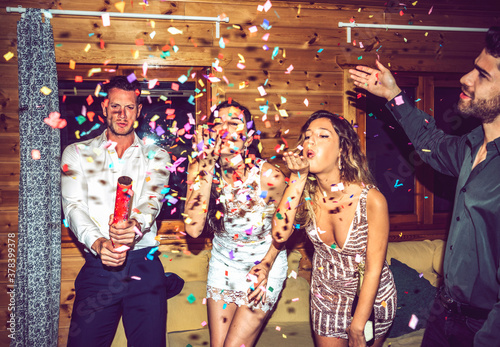 Happy male and female friends playing with confetti in party. photo