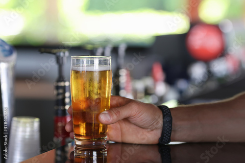 Man hand hold glass of cold beer. Service of visitors at bar.