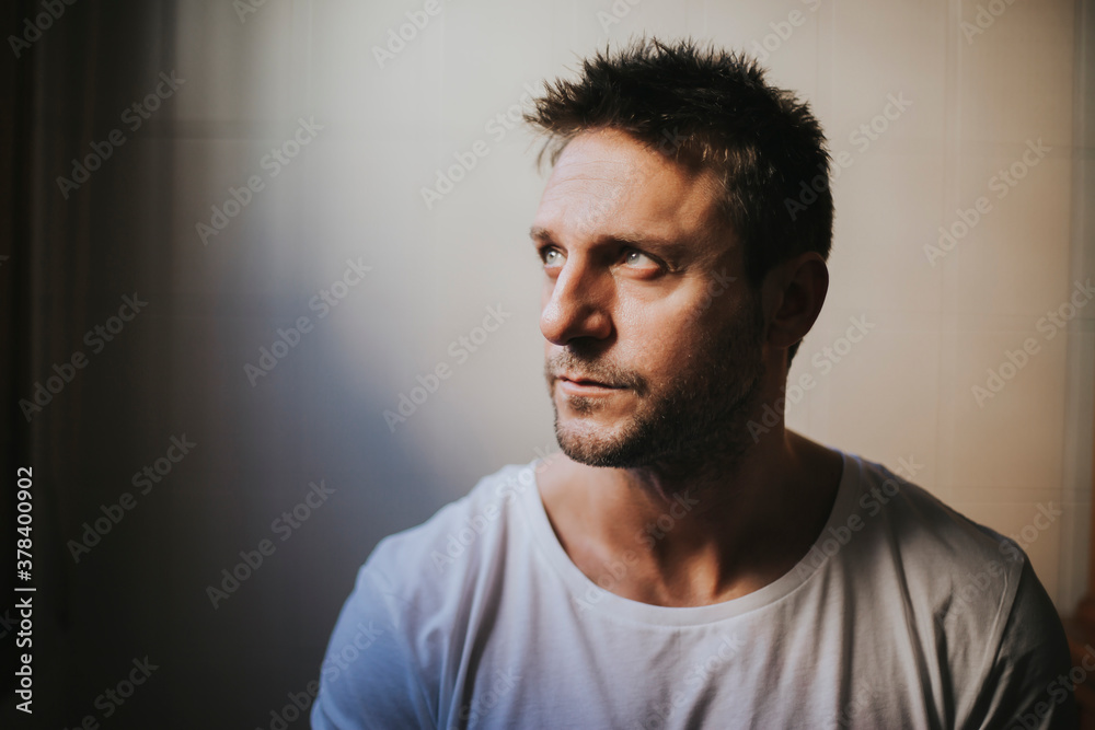 Close-up of thoughtful mid adult man looking away against wall at home Close-up of thoughtful mid adult man looking away against wall at home