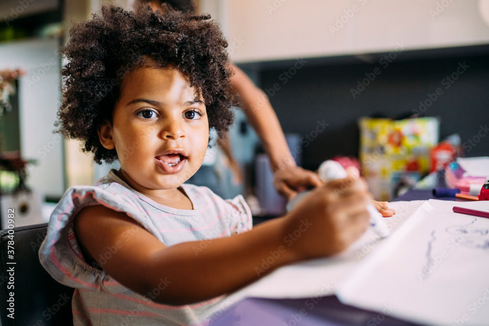 Close-up of cute baby girl drawing on paper at home