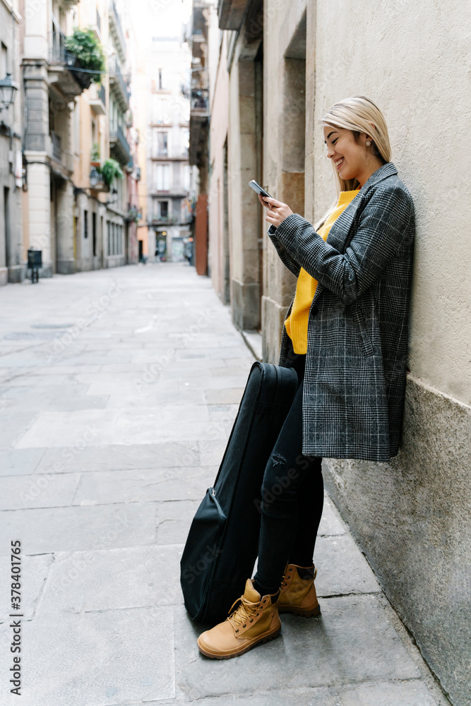 Young woman with violin case using smartphone in city Young woman with violin case using smartphone in city