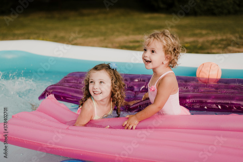 Two happy girls with airbed in an inflatable swimming pool
