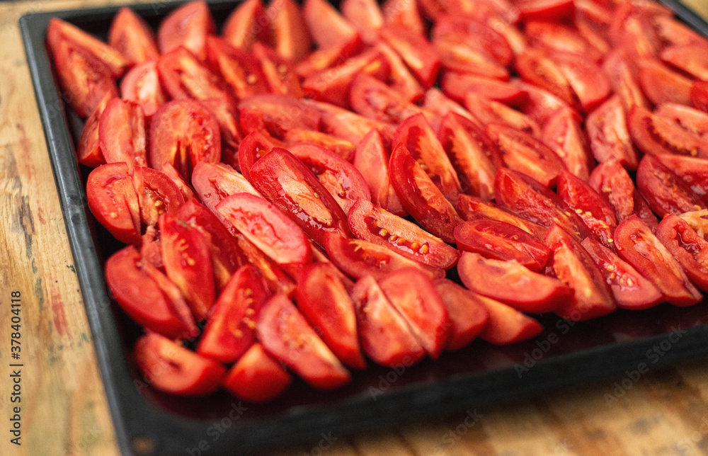  Tomatoes cut into wedges on a black pan. Tomato dishes. Tomato background.
