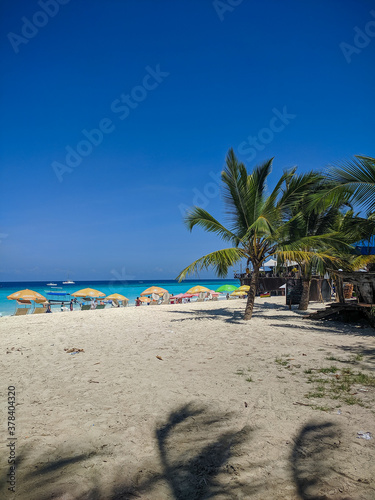 Zanzibar, Tanzania - December 3, 2019: Nungwi beach in Zanzibar, blue sea and blue ocean, on a beautiful tropical beach. Sun loungers with umbrellas. Vertical