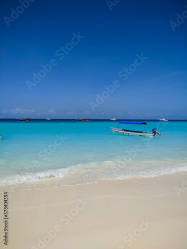 Zanzibar, Tanzania - December 3, 2019: Nungwi beach in Zanzibar, bright blue sea and blue sky on a beautiful white beach. The sailors' boats are on the shore for fishing and recreation. Vertical