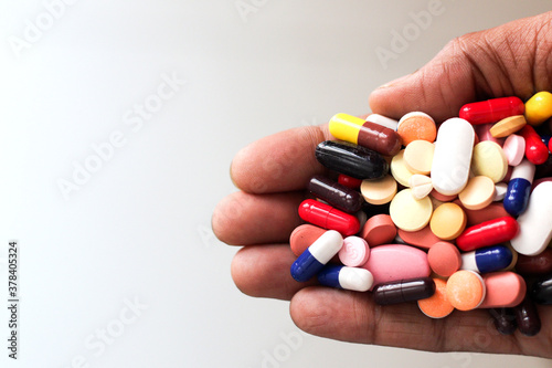 pile of medicine pills tablets capsules in a palm in white background