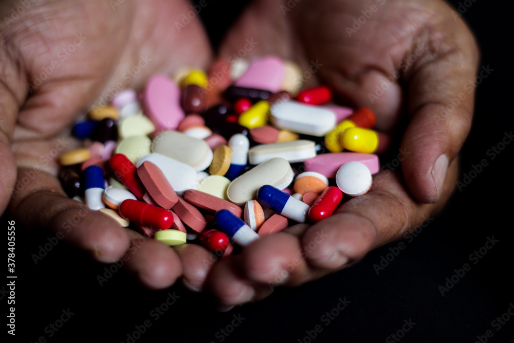 pile of medicine pills tablets capsules in a both hands in black background pile of medicine pills tablets capsules in a both hands in black background