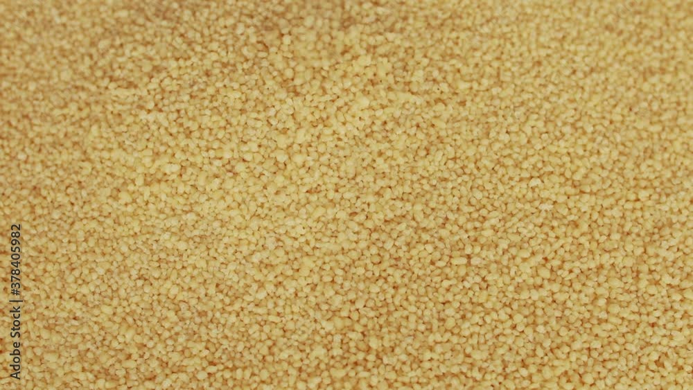 Raw organic couscous grains fall and crumble. Couscous background. Selective focus. Raw organic couscous grains fall and crumble. Couscous background. Selective focus.