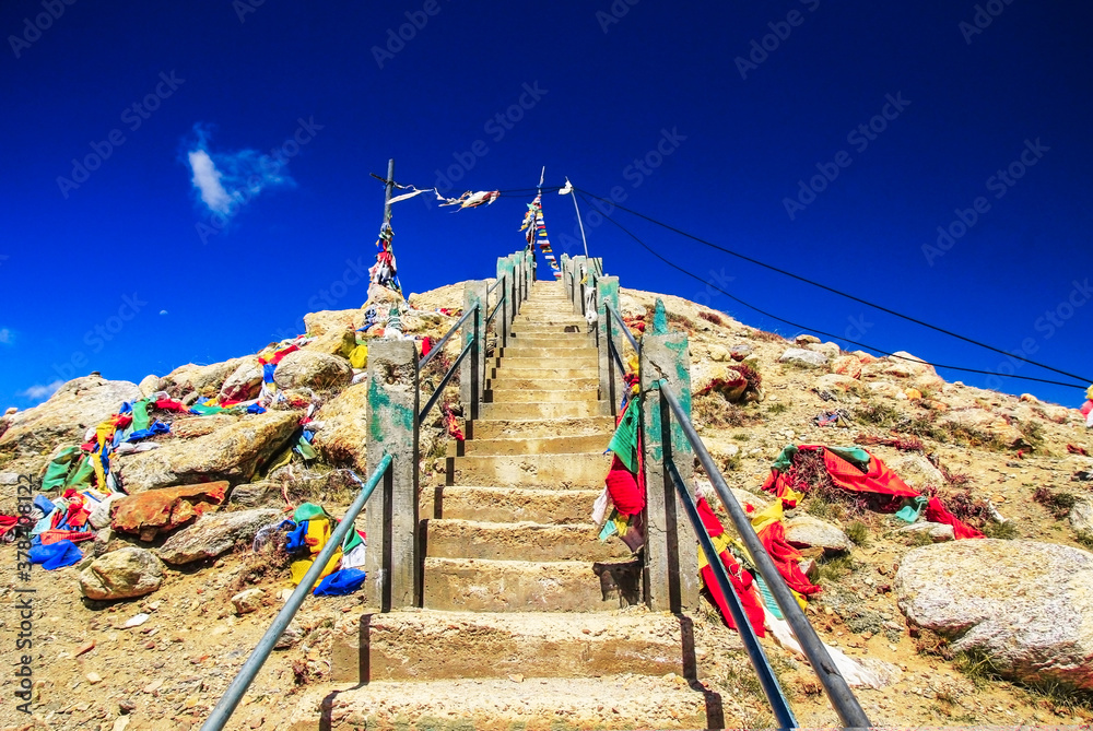 steep rock stairs with colourful flags rising up with deep blue sky