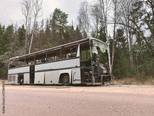 Broken bus abandoned in countryside. Old forgotten gray bus on the road in woods. landscape with shattered bus by the roadside