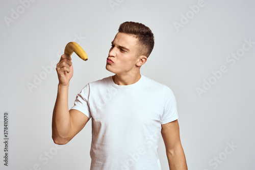 guy with a banana in his hand on a light background fun emotions light background white t-shirt model