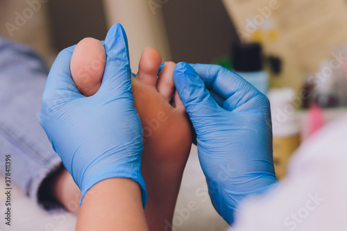 Canvas Print Therapist hands in protective gloves massaging woman's feet.