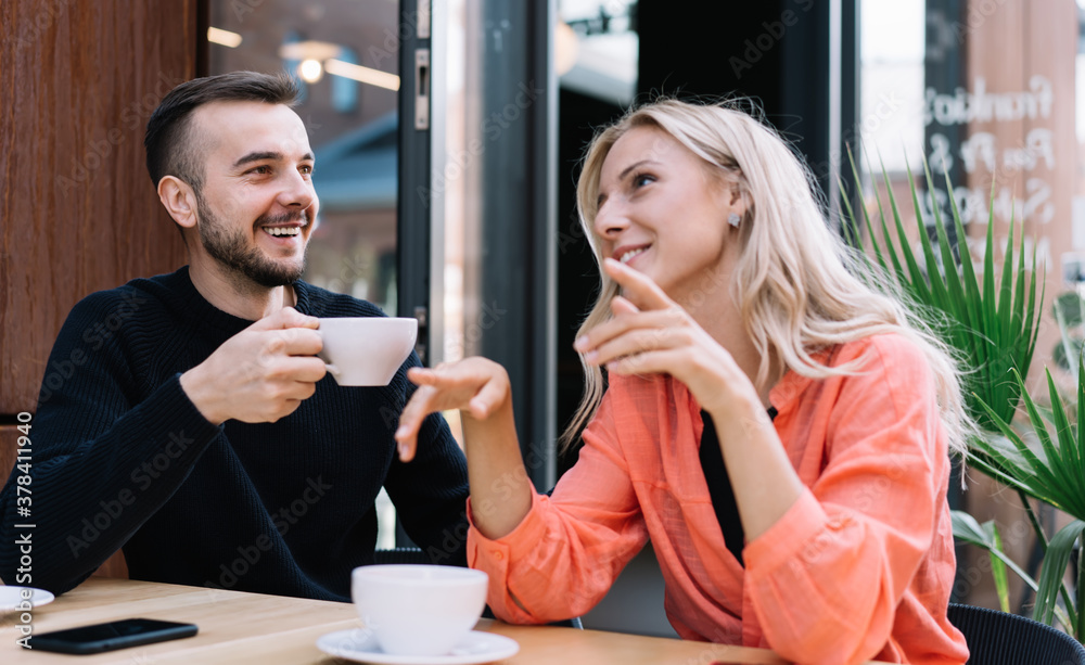 Cheerful couple sitting and talking in cafe