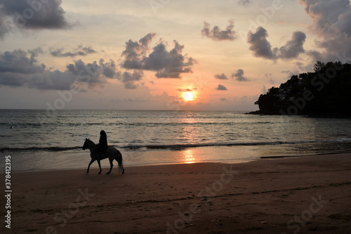 Silhouette of an unrecognizable woman riding on a horse on the beach during sunset. Photo taken in Thailand © Susie Hedberg