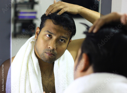 indian asian man looking after his appearance in front of a mirror beauty styling lifestyle.hair styling