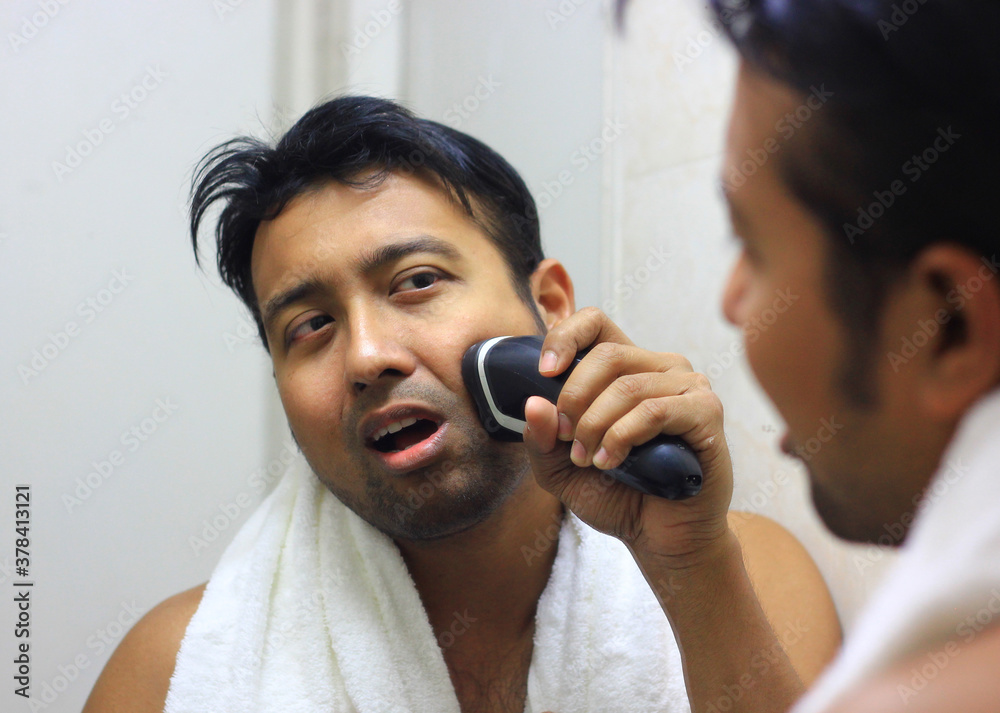 man looking after his appearance in front of a mirror beauty styling lifestyleman lookingIndian asian after his appearance in front of a mirror beauty styling lifestyle. Shaving routine man looking after his appearance in front of a mirror beauty styling lifestyleman lookingIndian asian after his appearance in front of a mirror beauty styling lifestyle. Shaving routine