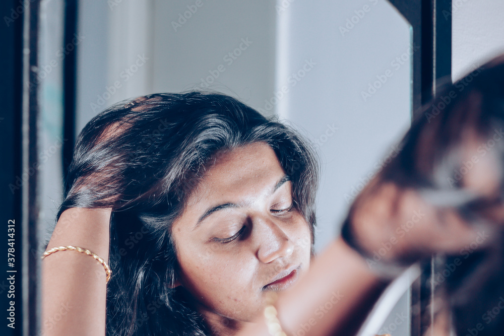 a lady handling and styling her hair by looking at mirror image