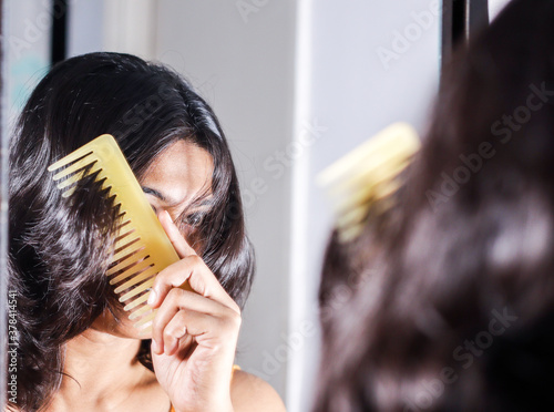 Foto lady combing her hair looking at her image at mirror.