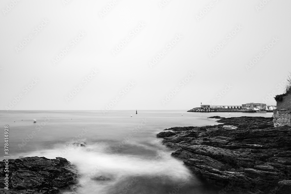 Rocks and small lighthouse on a calm foggy evening in the Rias Baixas in Galicia, Spain. Long exposure.