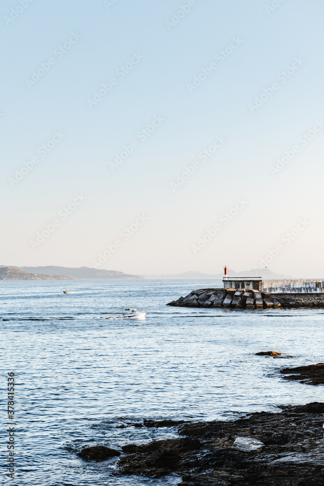 Small boat sailing back to port on a calm clear evening in the Rias Baixas in Galicia, Spain.