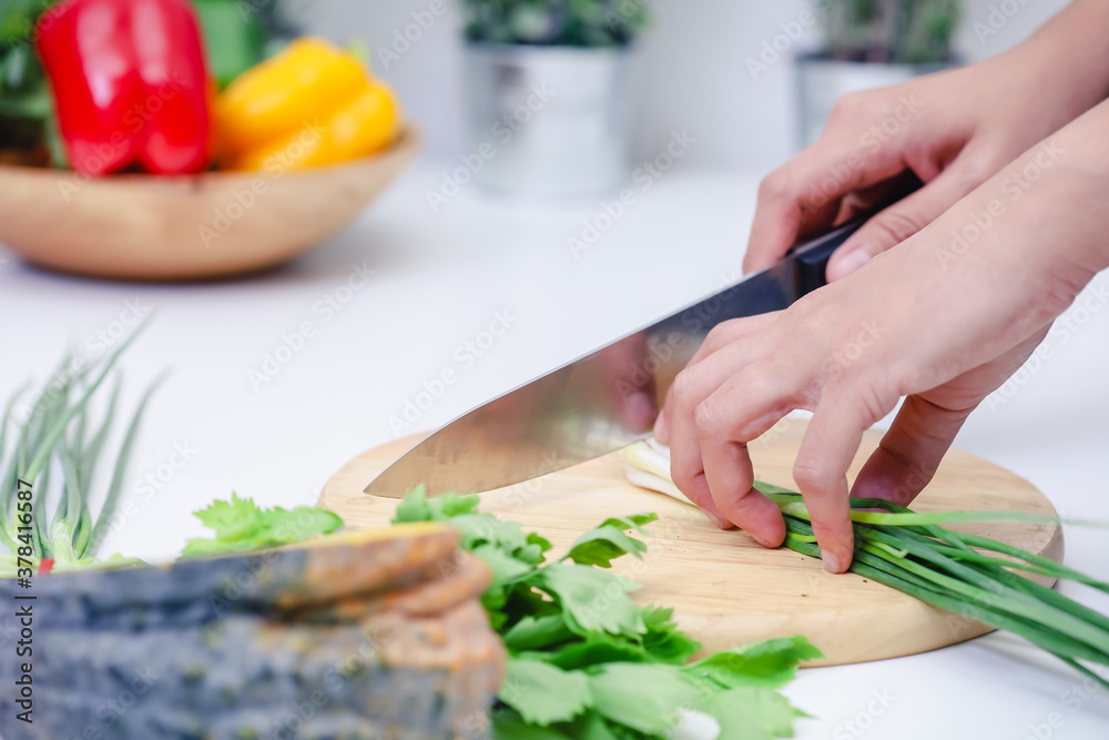 Woman hands cutting scallion in the kitchen. Chef cooking vegan food. Chef preparing vegetables in kitchen Woman hands cutting scallion in the kitchen. Chef cooking vegan food. Chef preparing vegetables in kitchen