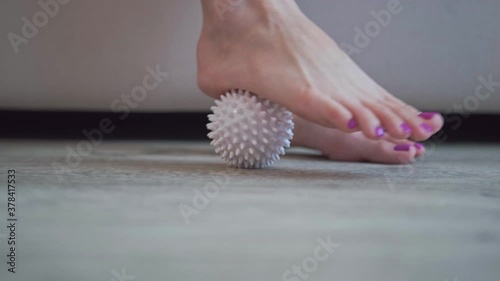 Close-up, a woman doing a foot massage with a special massage ball. The concept of prevention and treatment of flat feet.