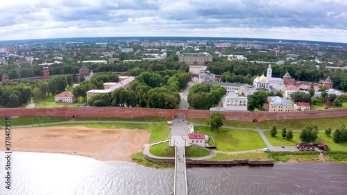 Panoramic aerial view of the Volkhov River and the old town of Veliky Novgorod, the red brick Kremlin in the rays of the setting sun and natural attractions of Russia.
