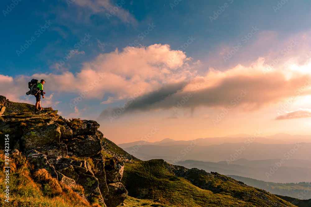 Naklejka premium A little boy standing on a large rocky rock admires the landscape of the Carpathians, the top of Mount Pip Ivan Chornohirsky.