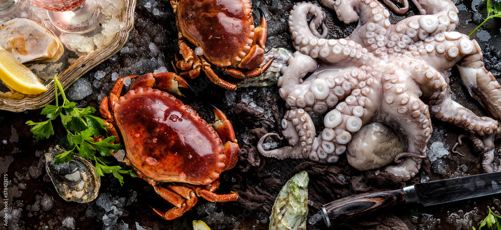 top view of delicious seafood with crabs, oysters, octopus, lemon slices, herbs and ice