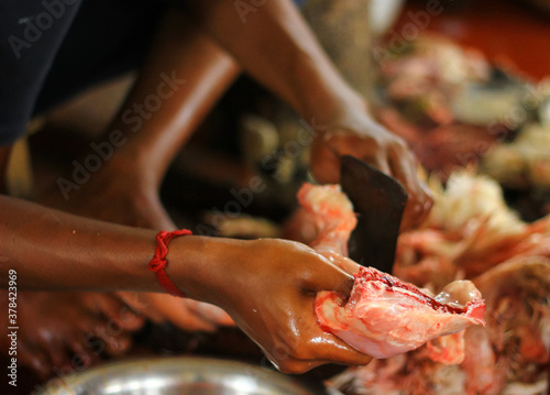 butcher cutting chicken on a standing blade dao with hand for sale