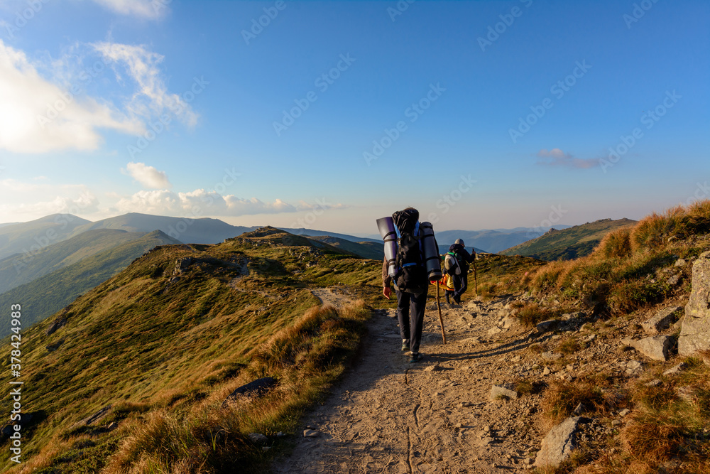 Three young tourists, two little boys and a teenager walk the trails of the Montenegrin ridge, around the top of the Carpathian mountains.