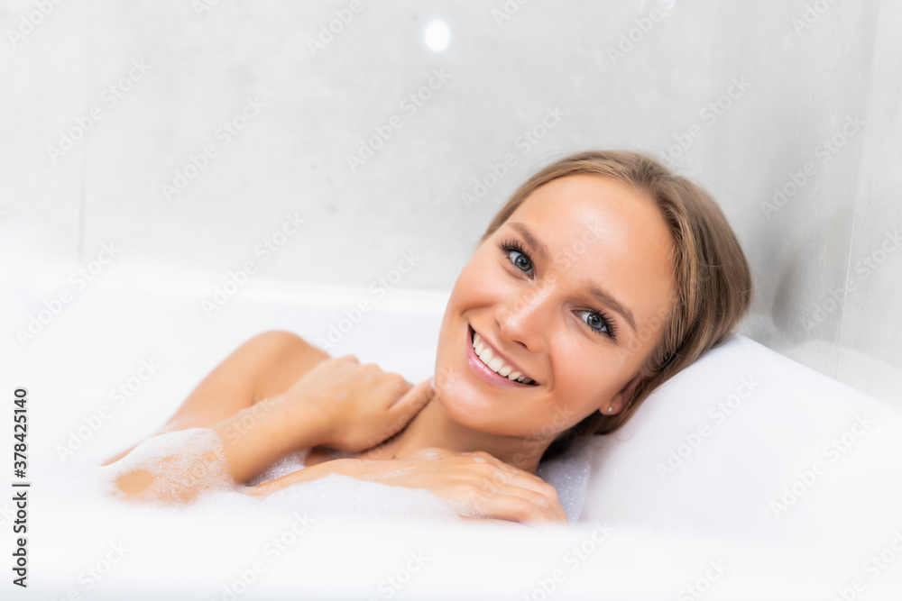 Obraz premium Close-up portrait of a young woman relaxing in the bathtube with smile