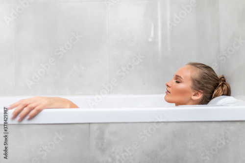 Young pretty woman lying in foam in the bathtub