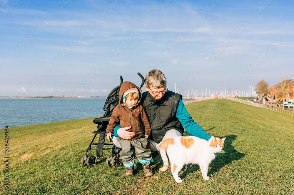 Fototapeta premium Man with toddler and cat on dyke