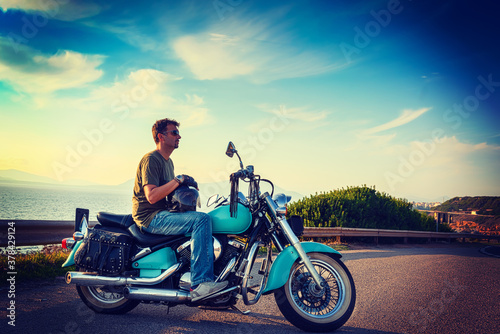 Biker and classic motorcycle parked by the sea