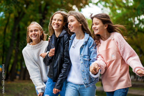 Four teenagers girls walking in autumn park