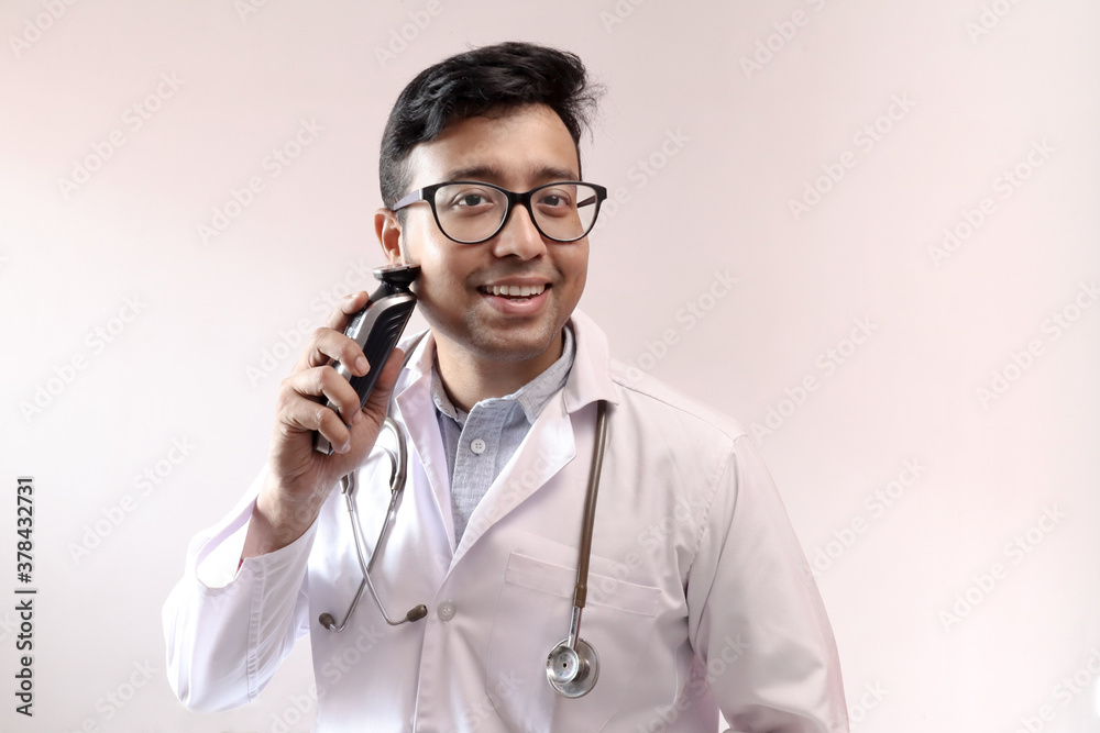 male indian doctor in white coat and stethoscope trimming beard with trimmer. doctor styling theme image male indian doctor in white coat and stethoscope trimming beard with trimmer. doctor styling theme image