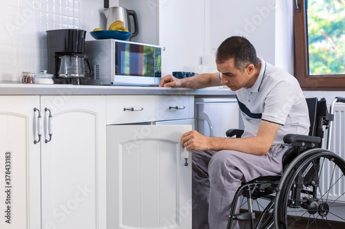 Young man sitting on wheelchair in kitchen