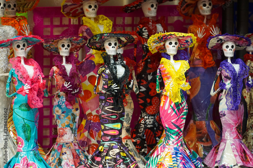 Small dolls for Dia de los Muertos, which means Day of the Dead in English. The dolls are on display at a market, and are bright and colourful.
