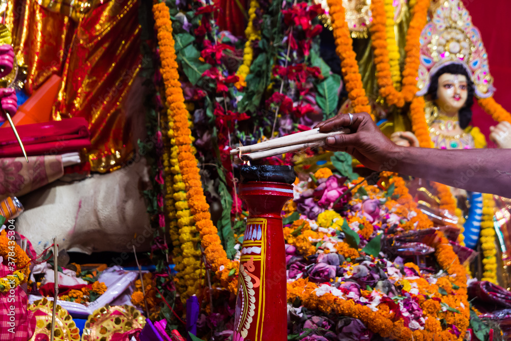 hand of a priest worshiping hindu god with garland and flower and fire