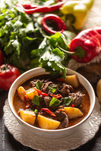 Bowl of goulash with meat, potatoes, chillies and parsley