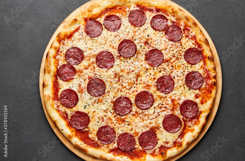 Delicious Italian Pizza pepperoni with mozzarella cheese and salami on dark background
