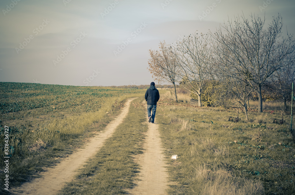 one man alone walking away on rural path